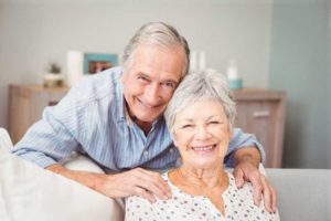 an elderly couple smiling after their dental implant restoration